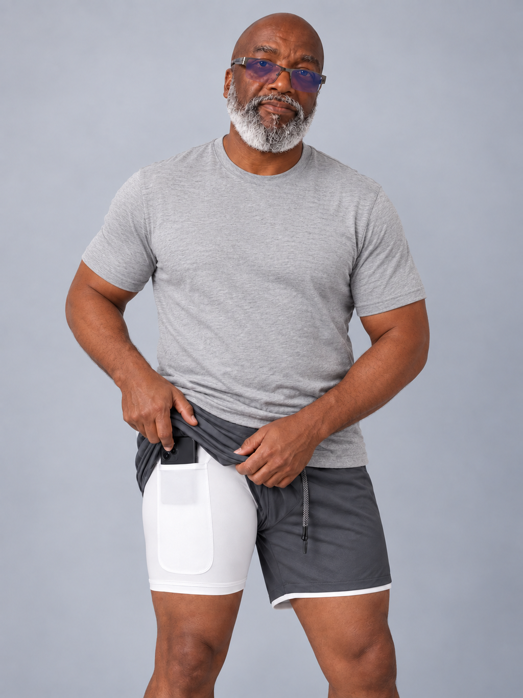 Model in a gray T-shirt wearing dark gray sports shorts, showing the white compression liner phone pocket